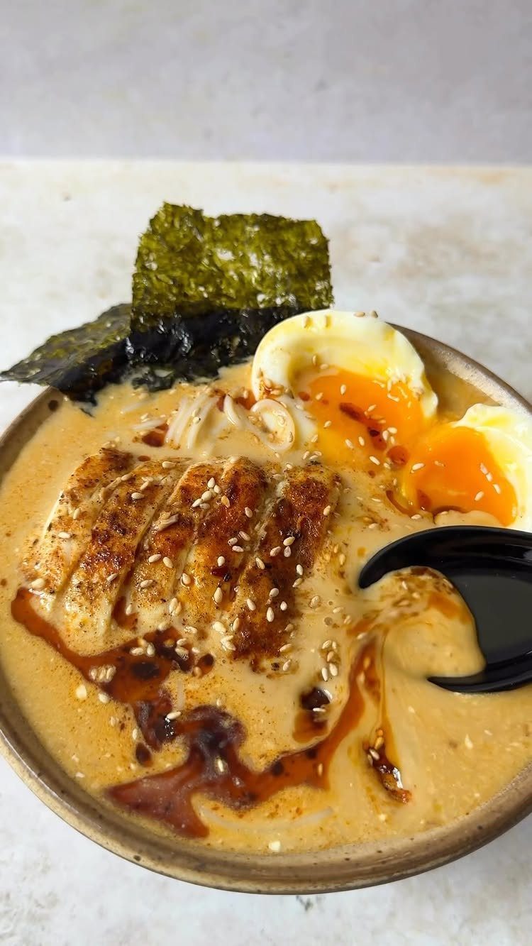 Ramen bowl with creamy broth, grilled chicken, soft-boiled egg, and nori seaweed.