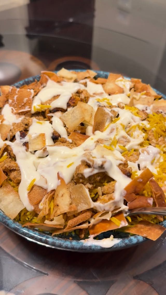 Lebanese Chicken Fatteh with toasted pita chips and creamy sauce in a blue bowl