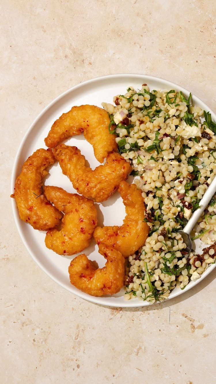 Fried breaded shrimp served with a fresh herb and grain salad on a plate.