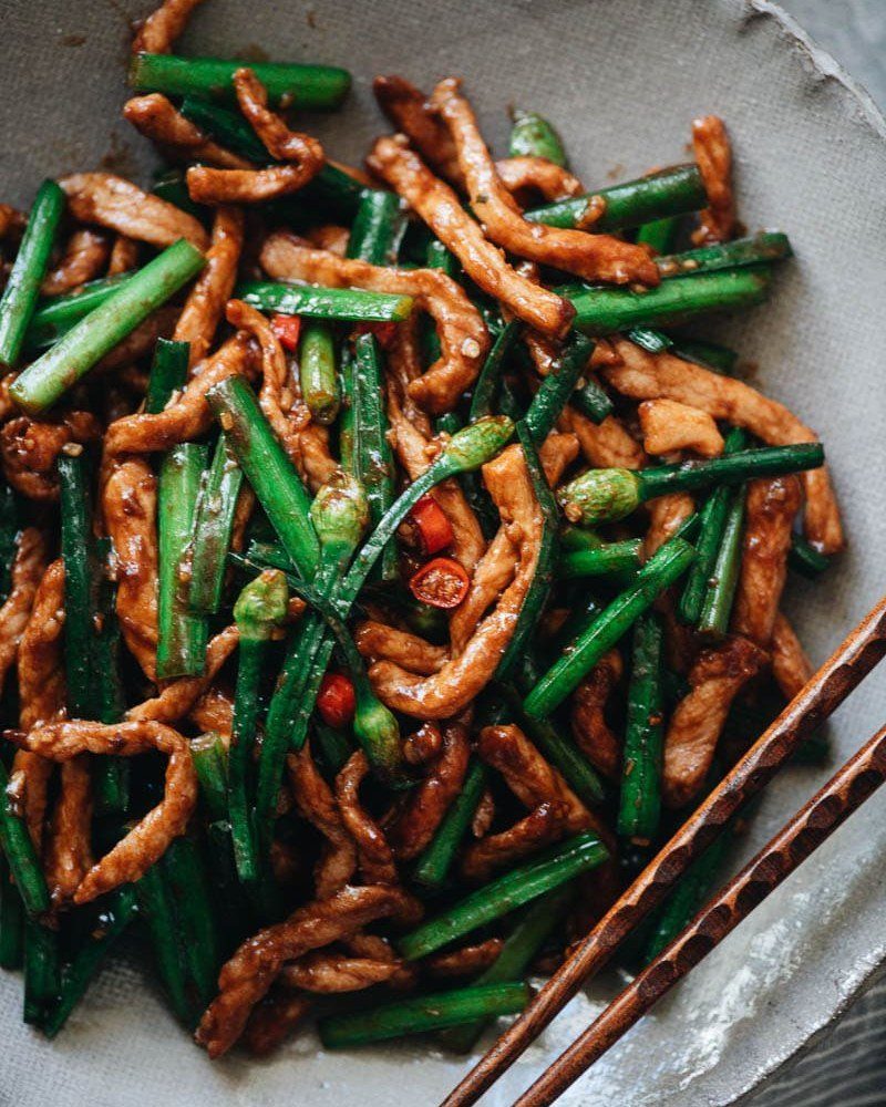 Stir-fried meat strips and green beans with chilies in a grey bowl.
