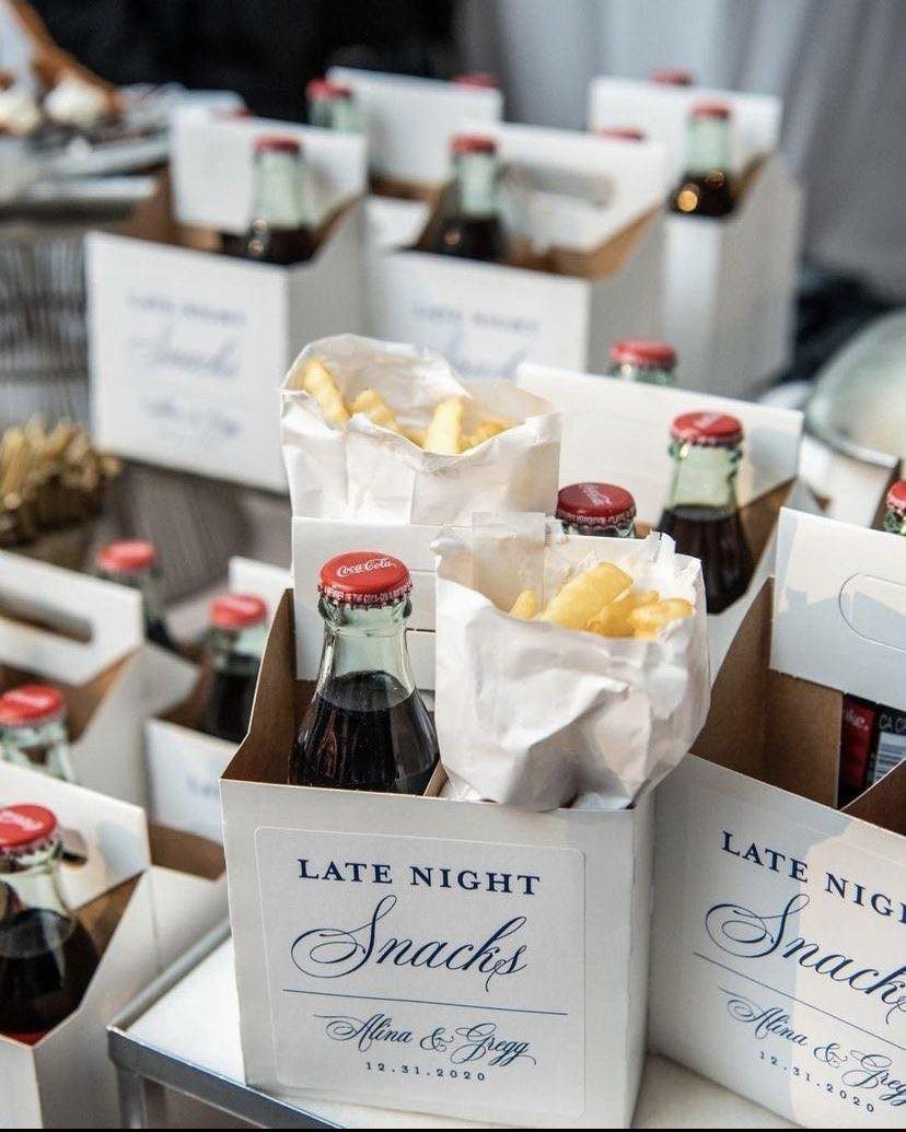 French fries in white paper cones and cola bottles in custom snack boxes.