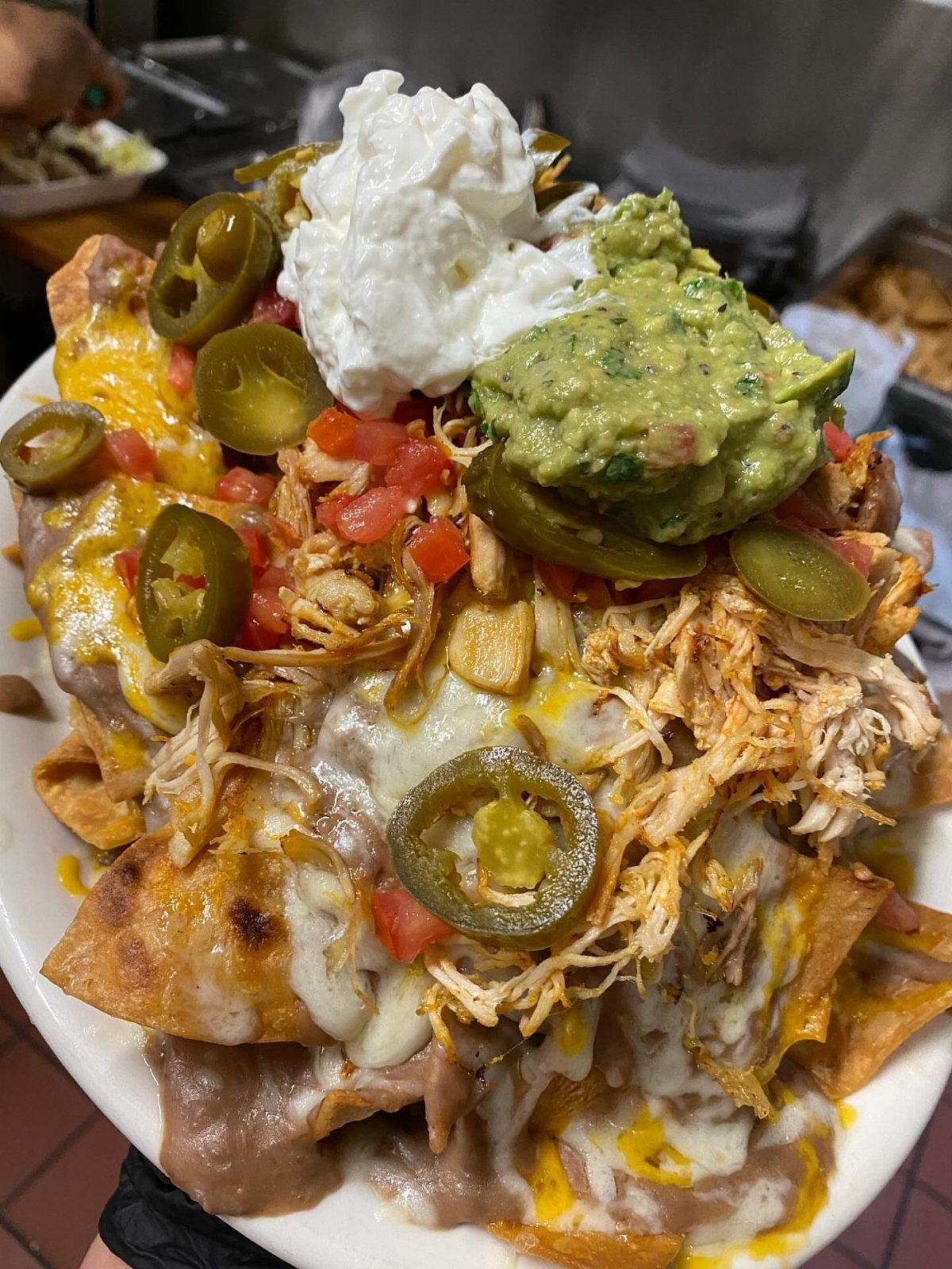 Loaded nachos with shredded chicken, melted cheese, guacamole, sour cream, and jalapeños.
