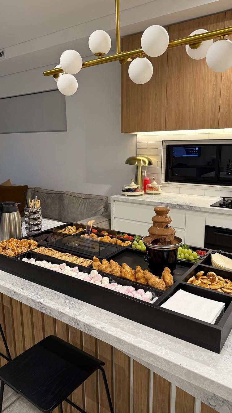 Dessert catering tray with chocolate fountain, marshmallows, and mini croissants on marble counter