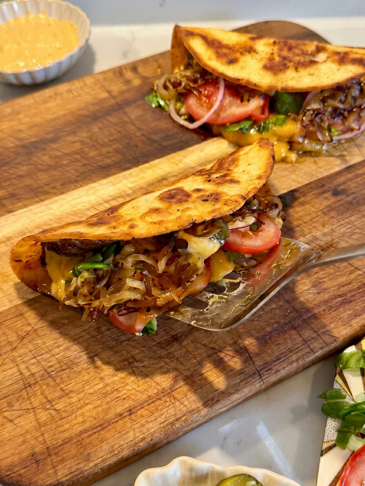 Toasted quesadillas with melted cheese and vegetables on a wooden cutting board.