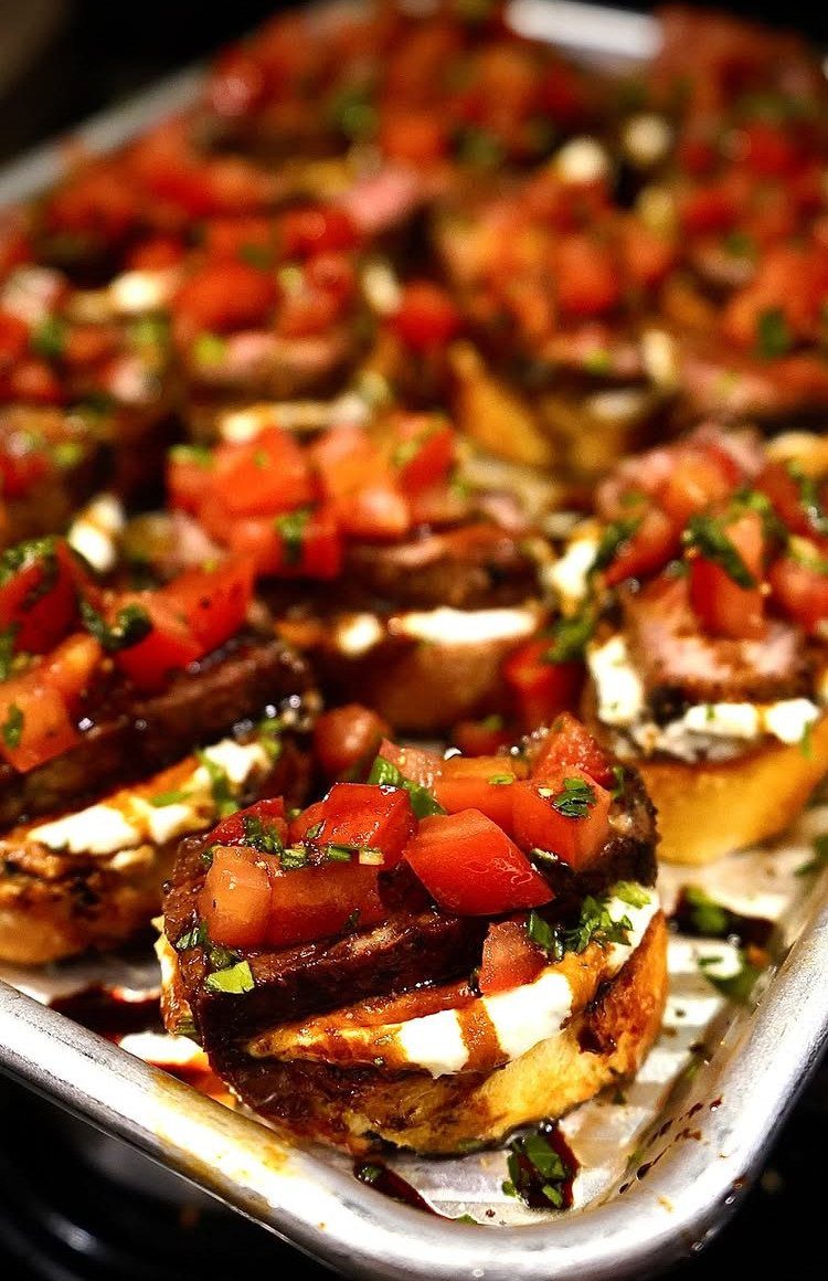Toasted baguette slices topped with creamy cheese, diced tomatoes, and balsamic glaze.