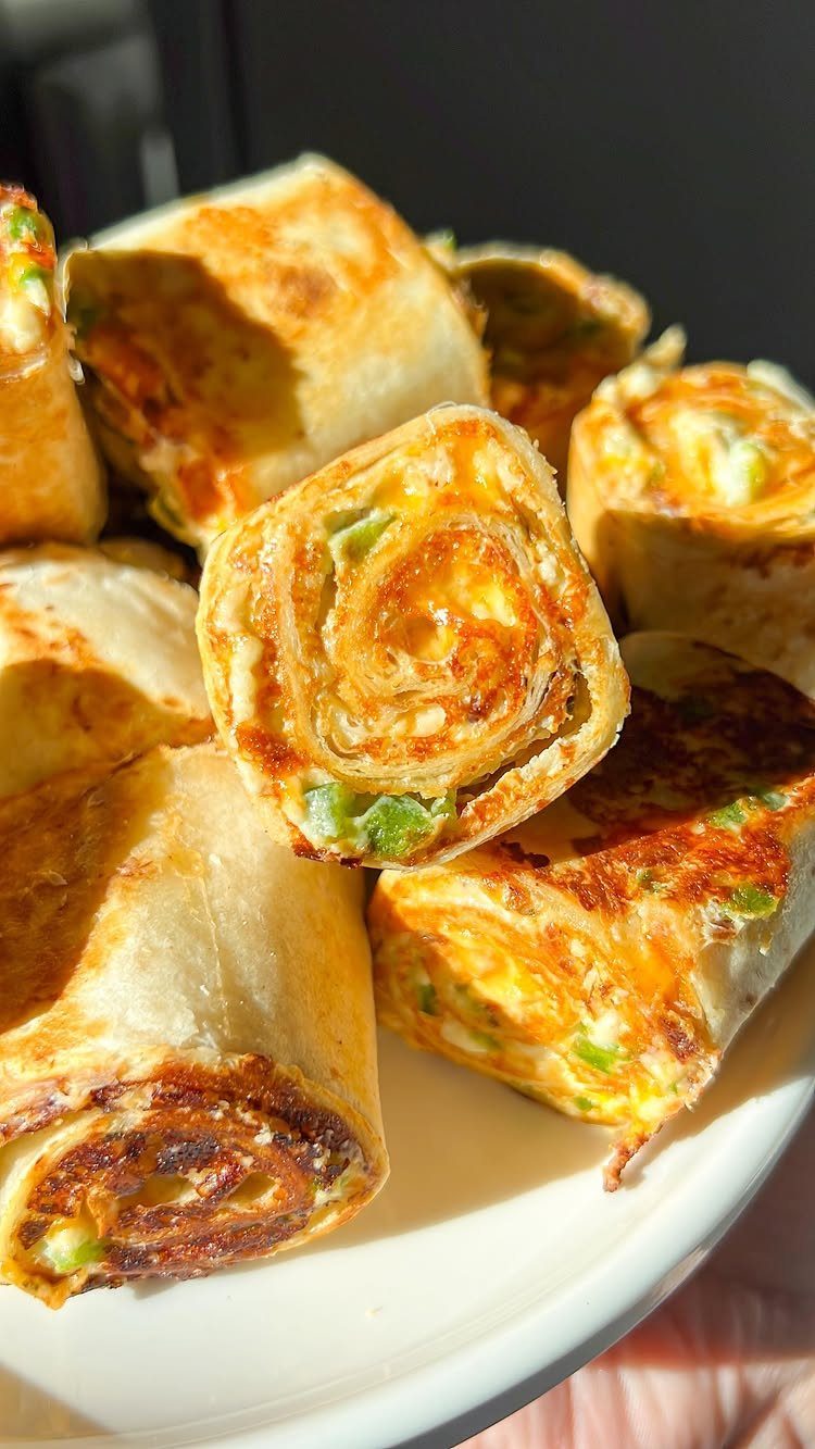 Toasted pinwheel sandwiches with melted cheese and green peppers on a white plate.