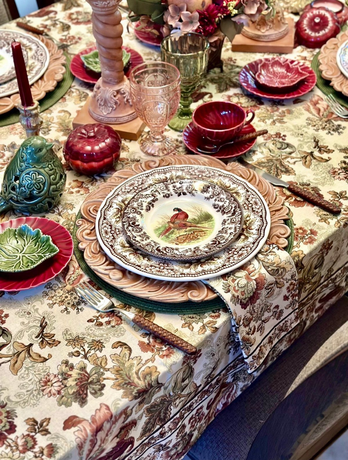 Floral table setting with layered plates, colorful glassware, and autumn decorations.