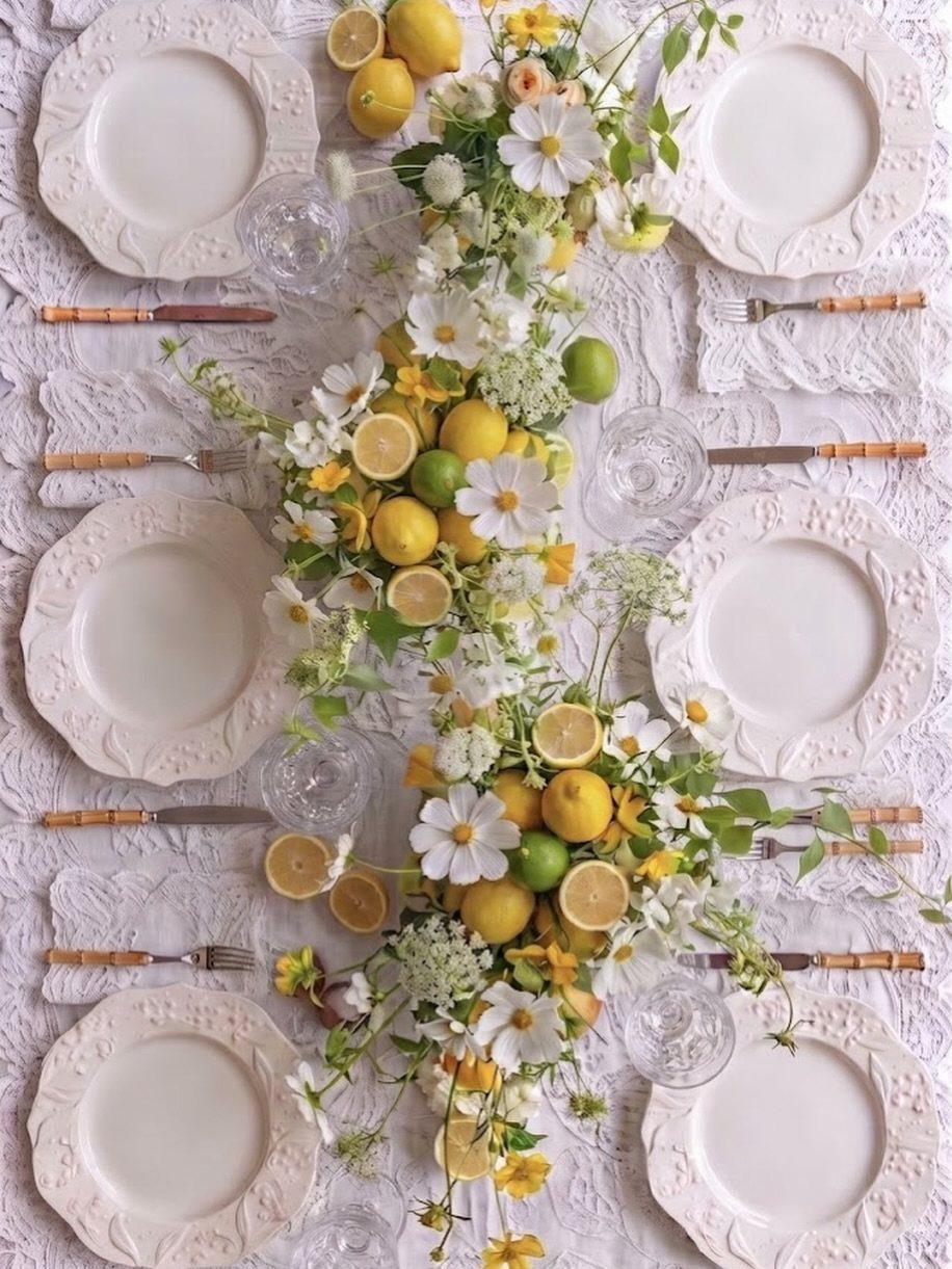 White table setting with a lemon and white daisy floral centerpiece runner.