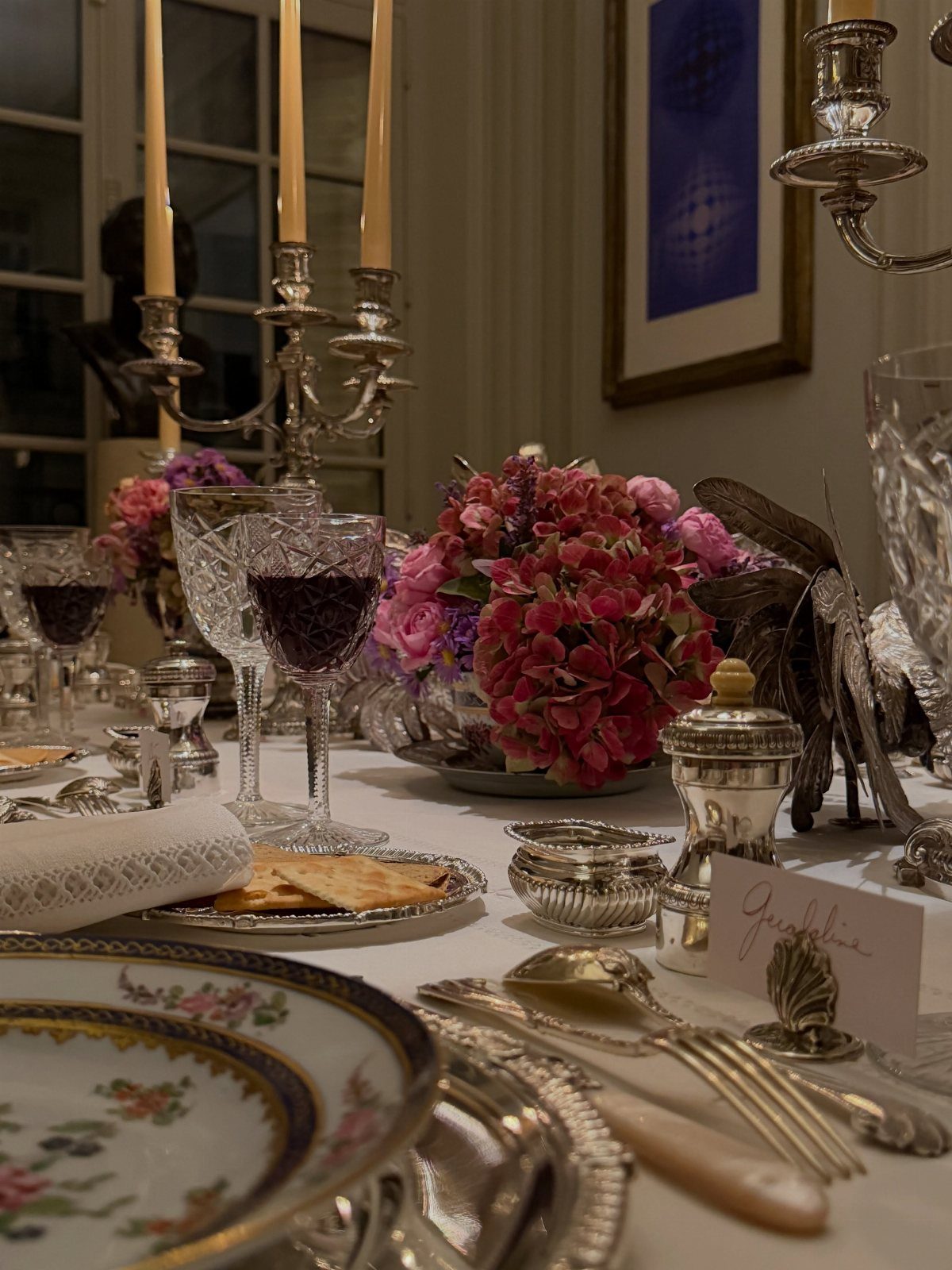 Elegant table setting with silver candelabras, pink hydrangeas, and ornate floral china.