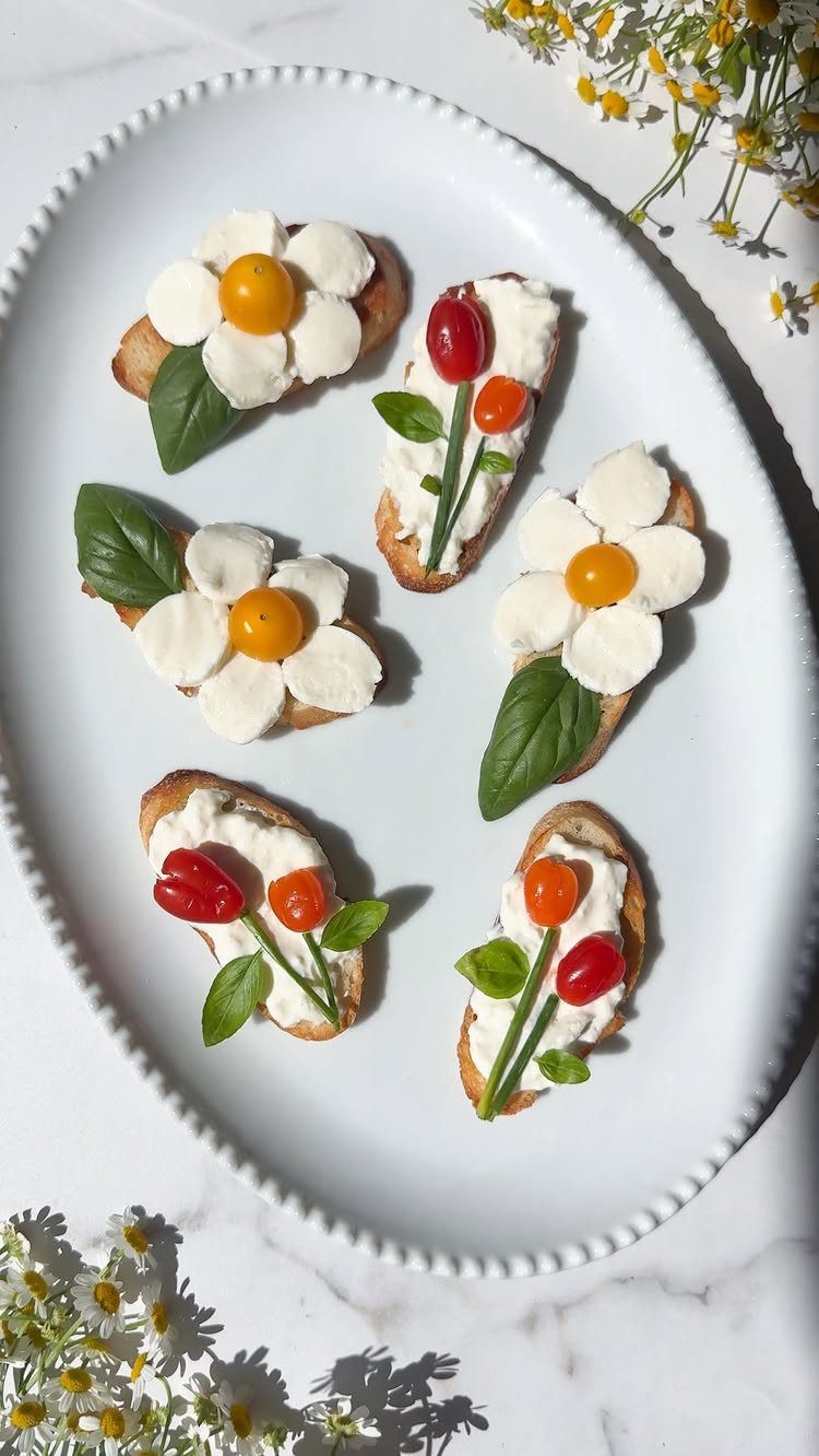 Toasted baguette slices topped with mozzarella and tomatoes arranged as colorful flowers.