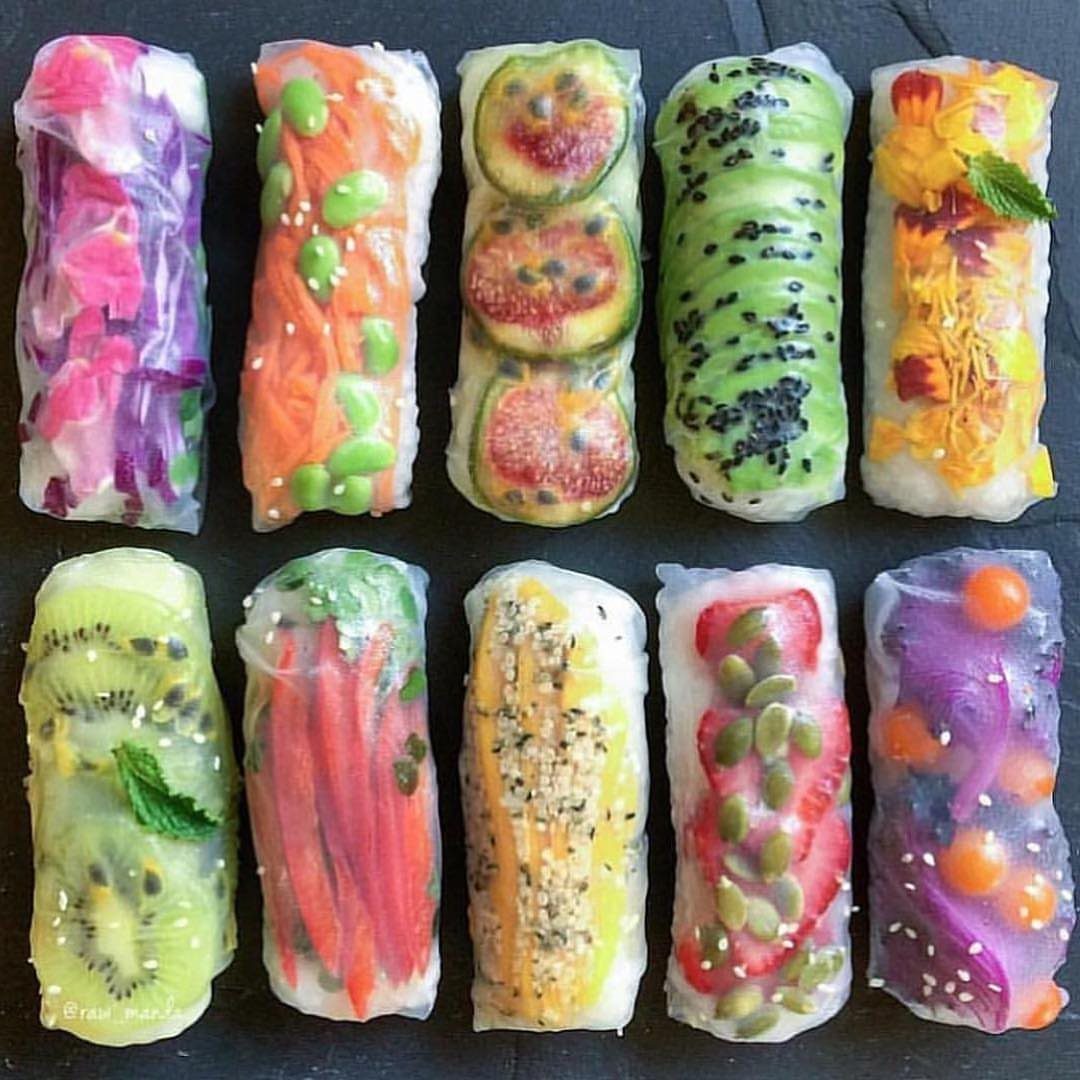 Colorful vegetable and fruit spring rolls wrapped in translucent rice paper on dark background