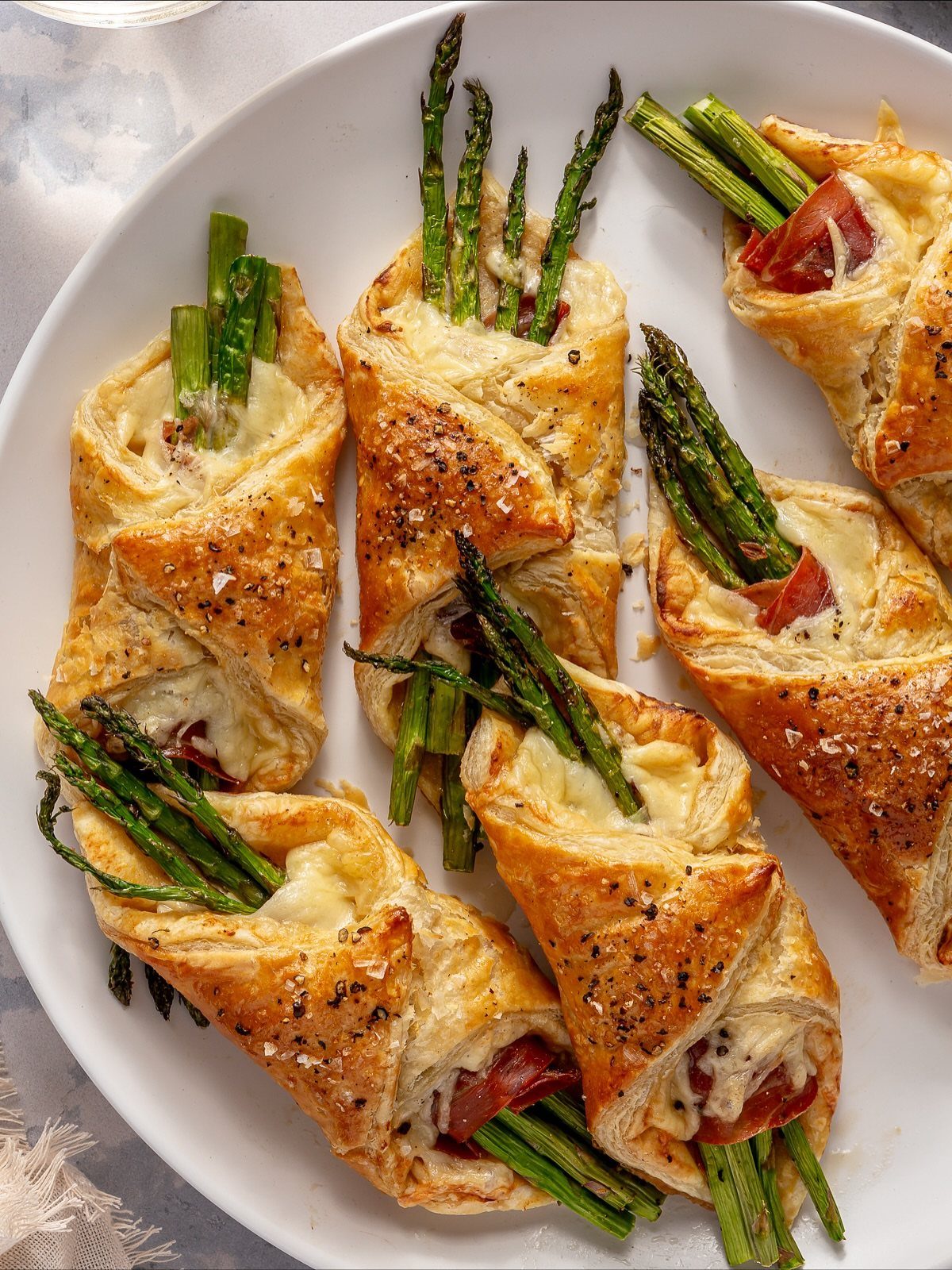 Asparagus and cheese wrapped in golden puff pastry on a white plate