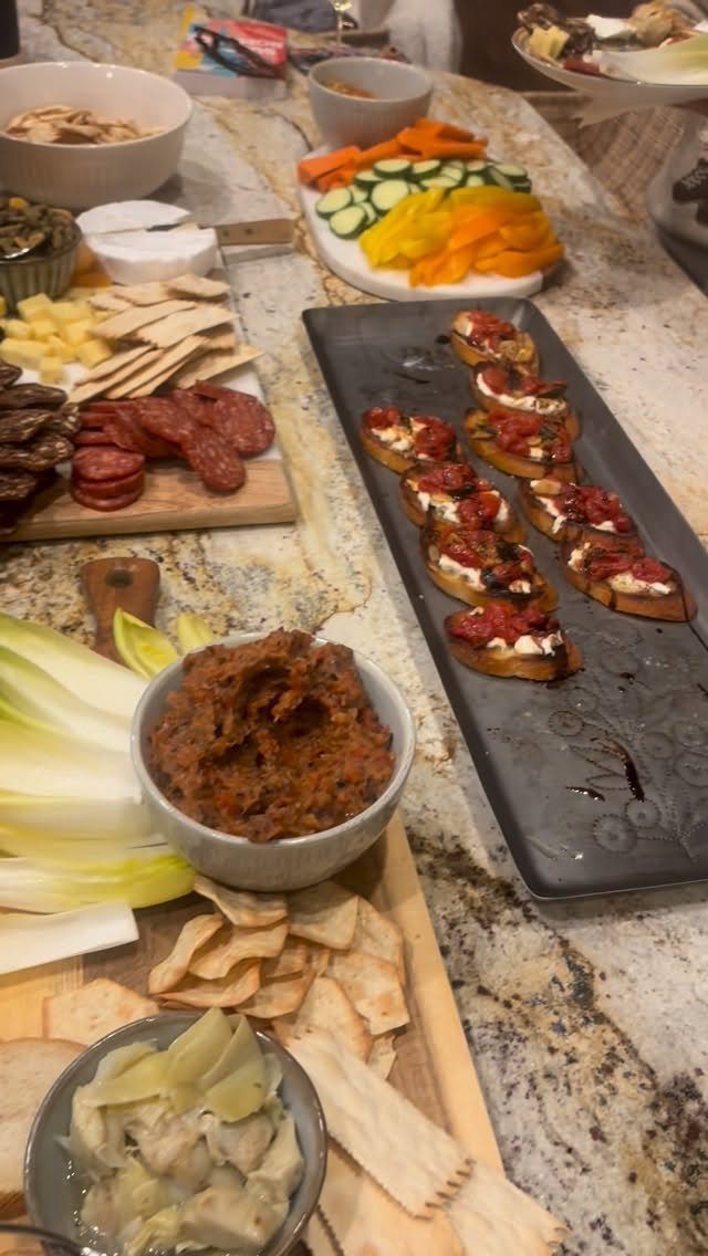 Assorted appetizers including a charcuterie board, crostini, and vegetable platter on a counter.