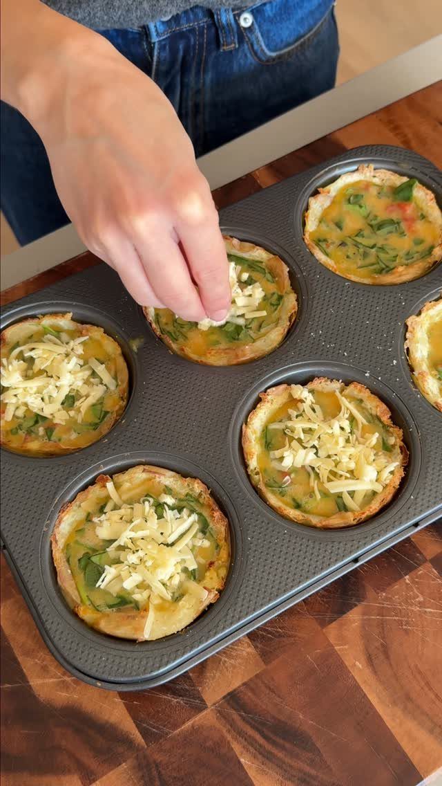 Mini quiches with spinach and cheese in a muffin tin on wooden counter