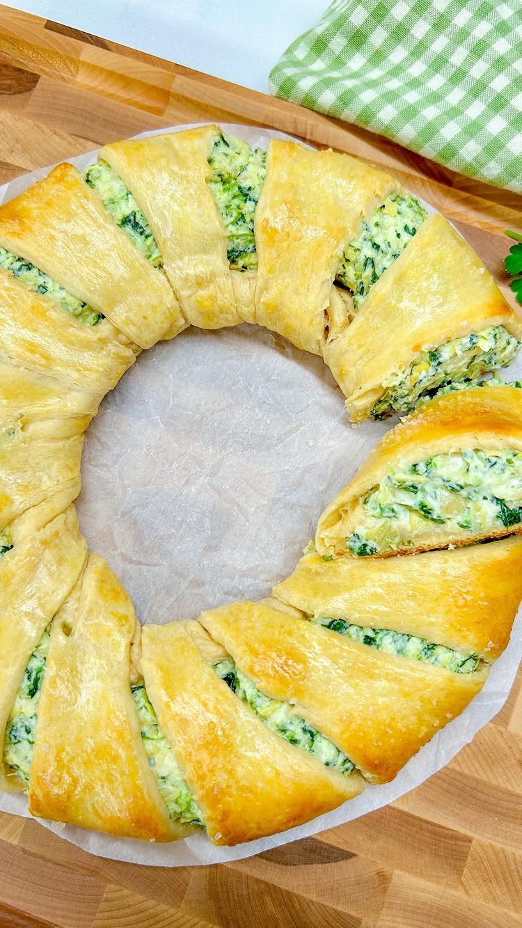 Spinach and artichoke puff pastry rolls arranged in a circle on parchment paper.