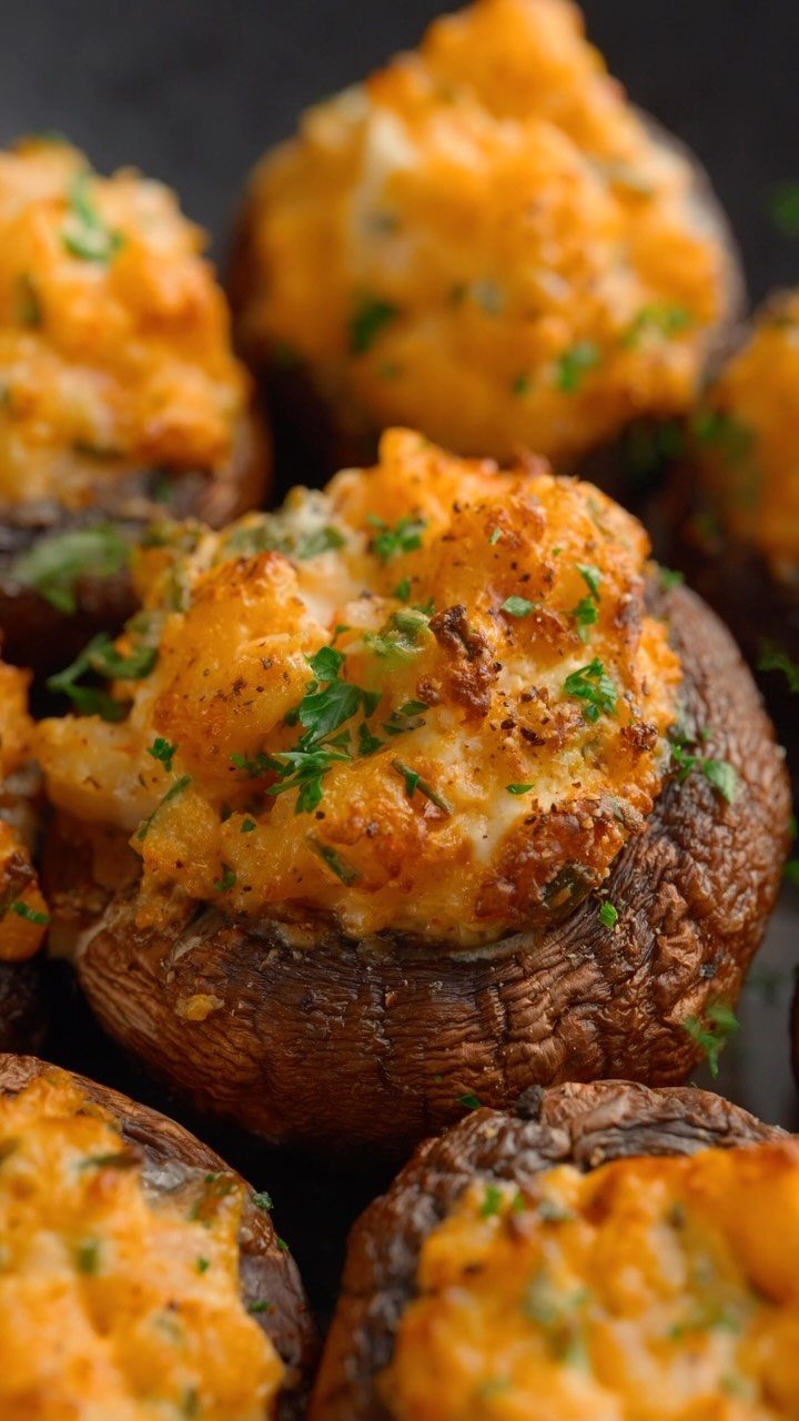 Stuffed mushroom caps with golden cheese filling and fresh parsley garnish.