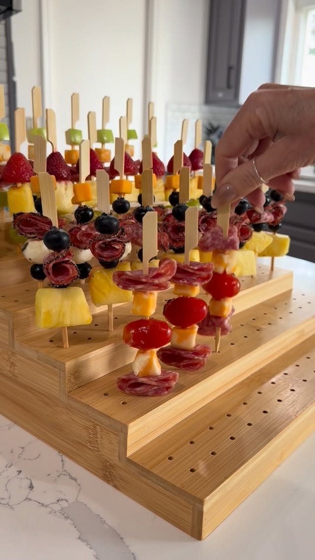 Antipasto skewers with salami and cheese on a tiered wooden display stand.