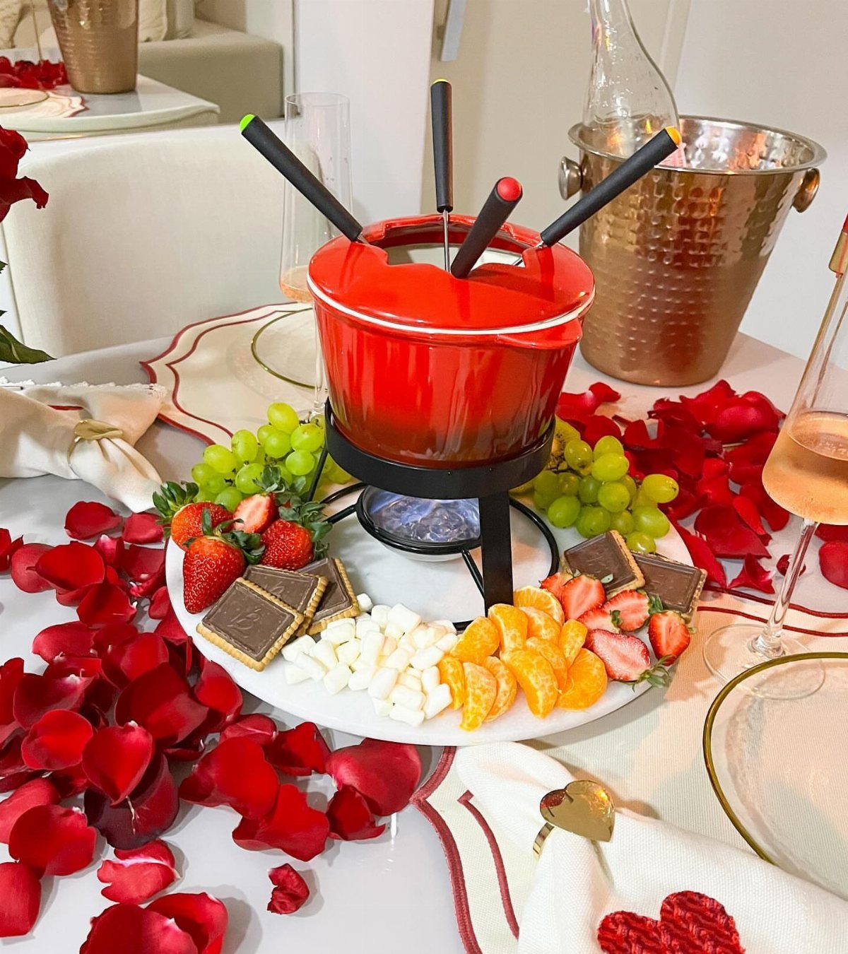 Red fondue pot with dipping fruits and sweets on a rose petal table