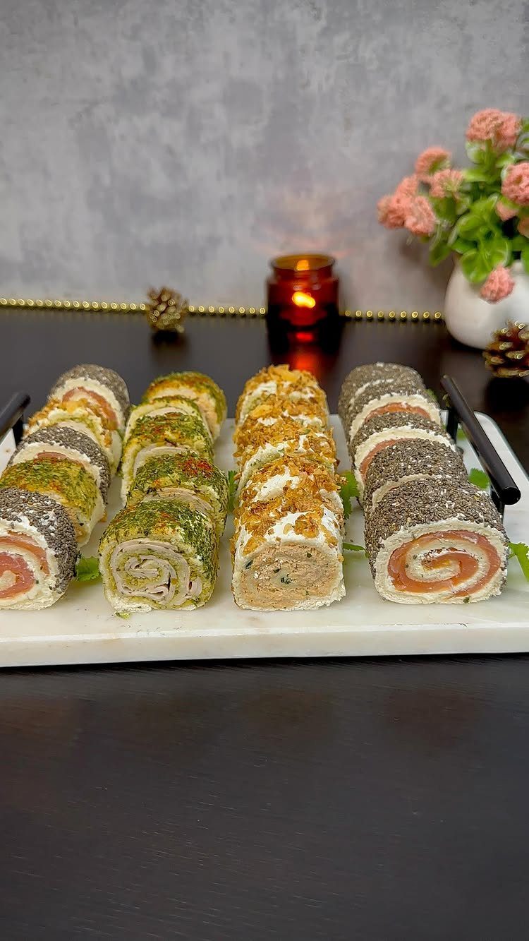 Pinwheel sandwiches with colorful coatings arranged on a white marble serving platter.