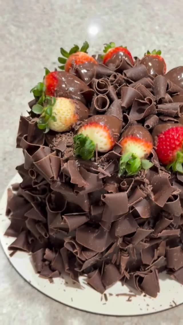 Chocolate cake covered in chocolate curls and topped with chocolate-dipped strawberries.