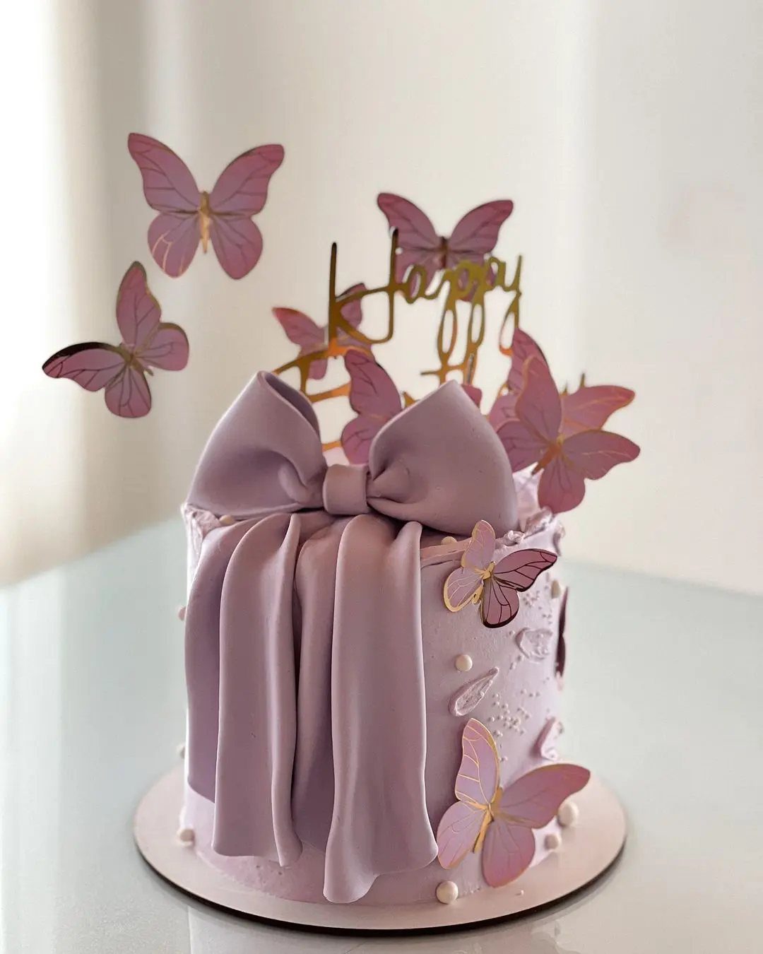 Purple birthday cake with a large fondant bow and decorative purple butterflies.
