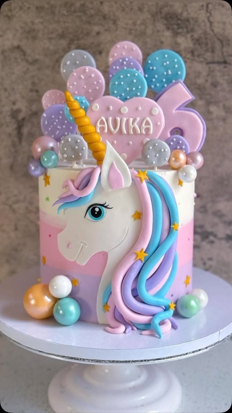 Unicorn cake with pastel frosting, golden horn, and a pink heart topper.