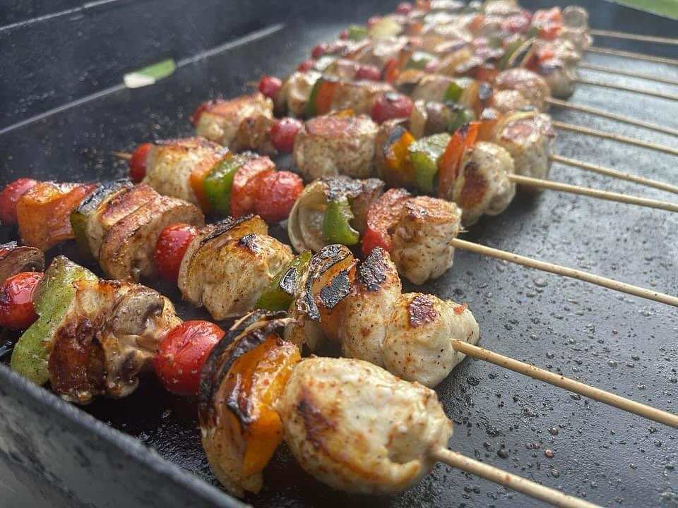 Grilled chicken and vegetable shish kabobs with peppers and tomatoes on a grill.