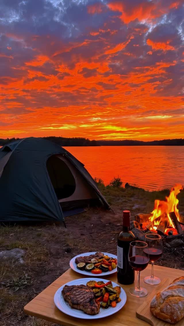 Grilled steak and vegetables with red wine on a table by a campfire.