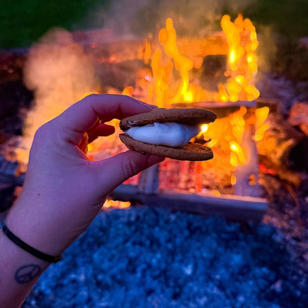S'more with toasted marshmallow and graham crackers held in front of a campfire