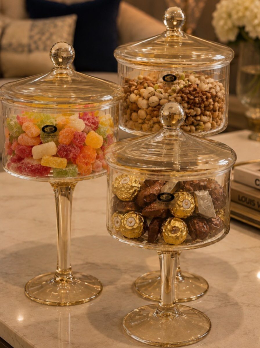 Clear glass apothecary jars filled with colorful gummies, nuts, and gold chocolates.
