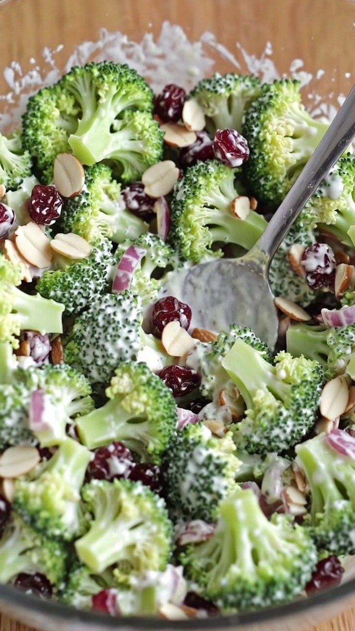 Broccoli salad with dried cranberries, sliced almonds, and creamy dressing in a bowl