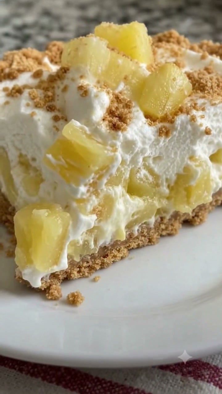 Pineapple pie slice with whipped cream and pineapple chunks on a white plate