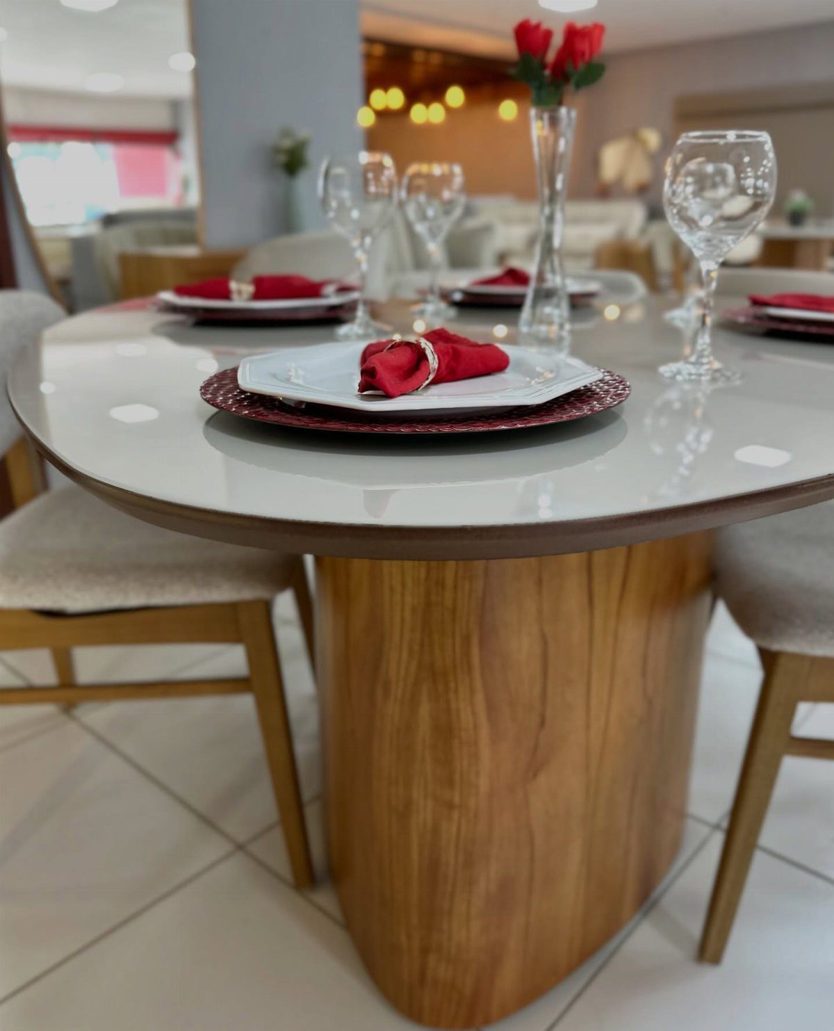 Round glass dining table set with white plates, red napkins, and wine glasses.