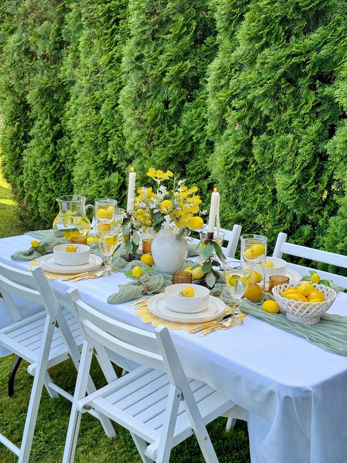 Outdoor table setting with yellow lemons, yellow flowers, and light green napkins.