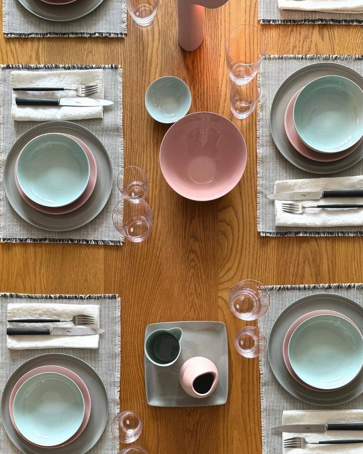 Grey and light blue dinnerware arranged on a wooden table with placemats.