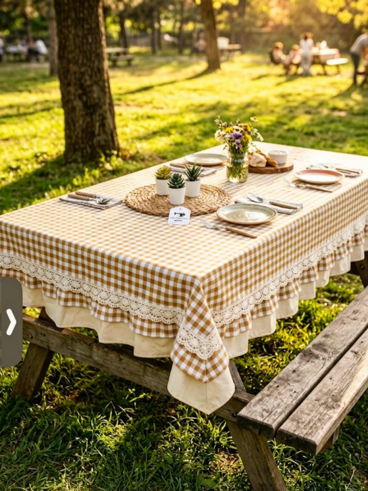 Yellow gingham checkered tablecloth with lace trim on an outdoor picnic table setting
