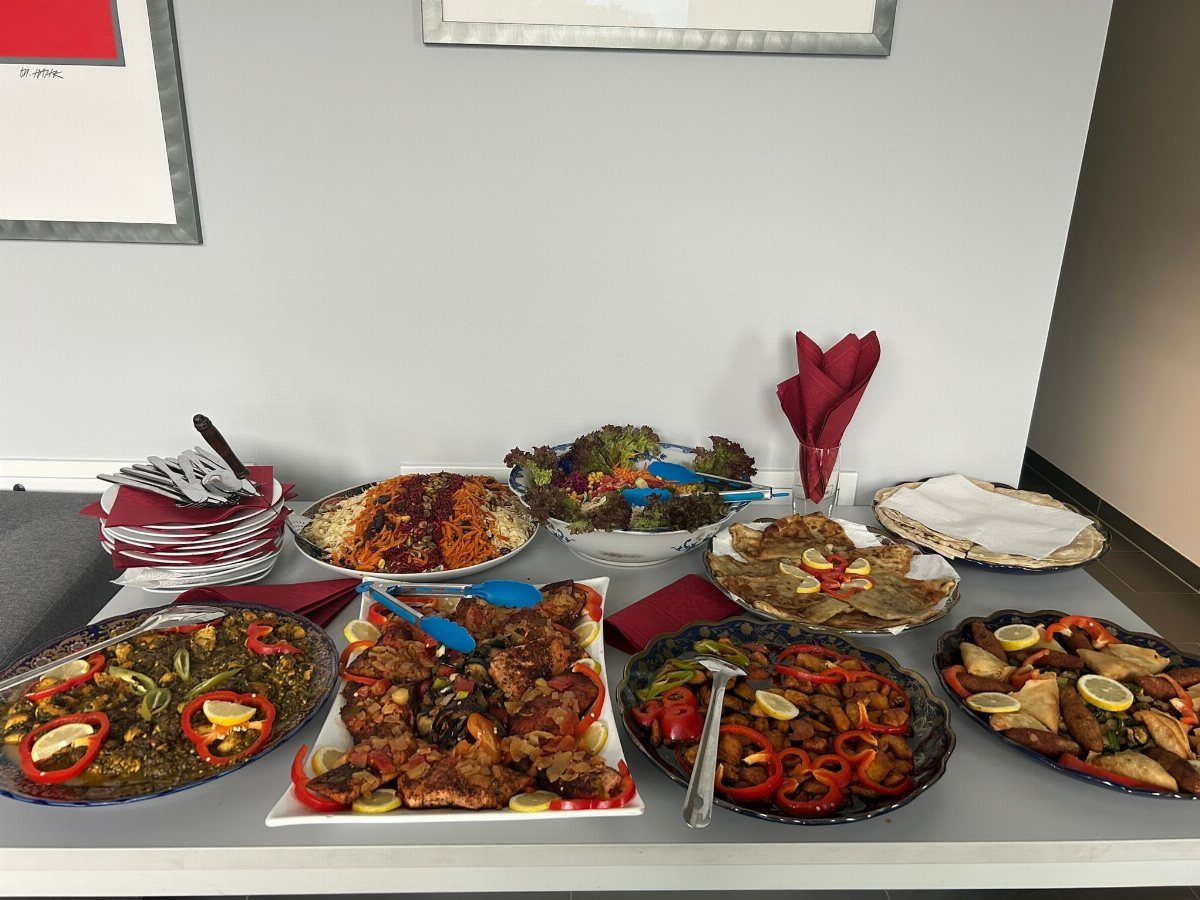 Assorted food platters with grilled meats and vegetables on a white table.