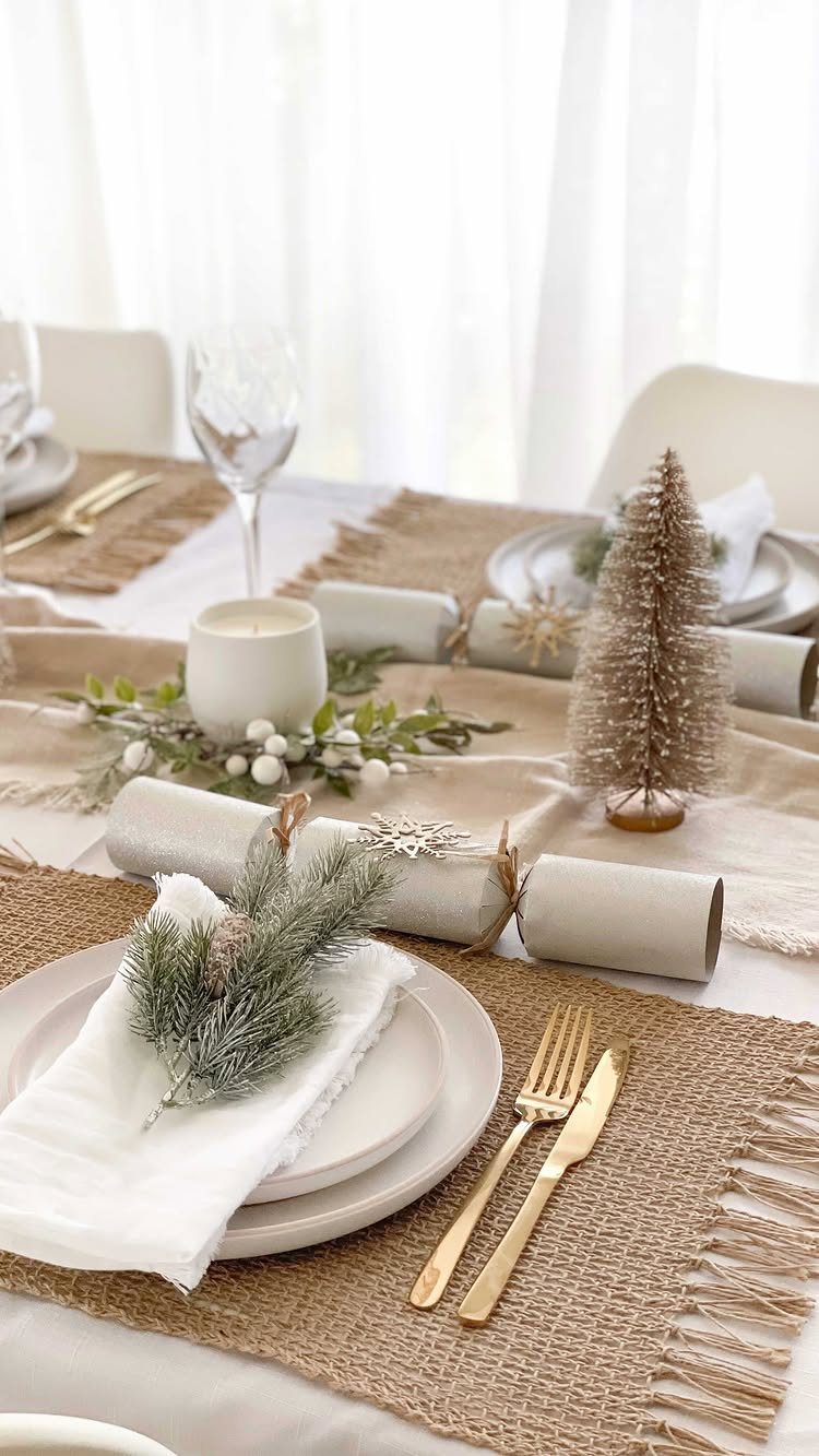 White plates and gold cutlery on a burlap mat with a gold tree.