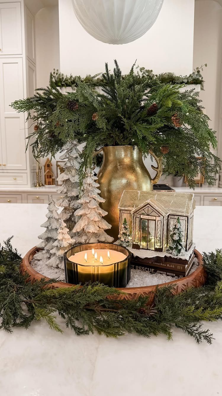 Festive centerpiece with evergreen branches in a gold pitcher and snowy miniature trees.