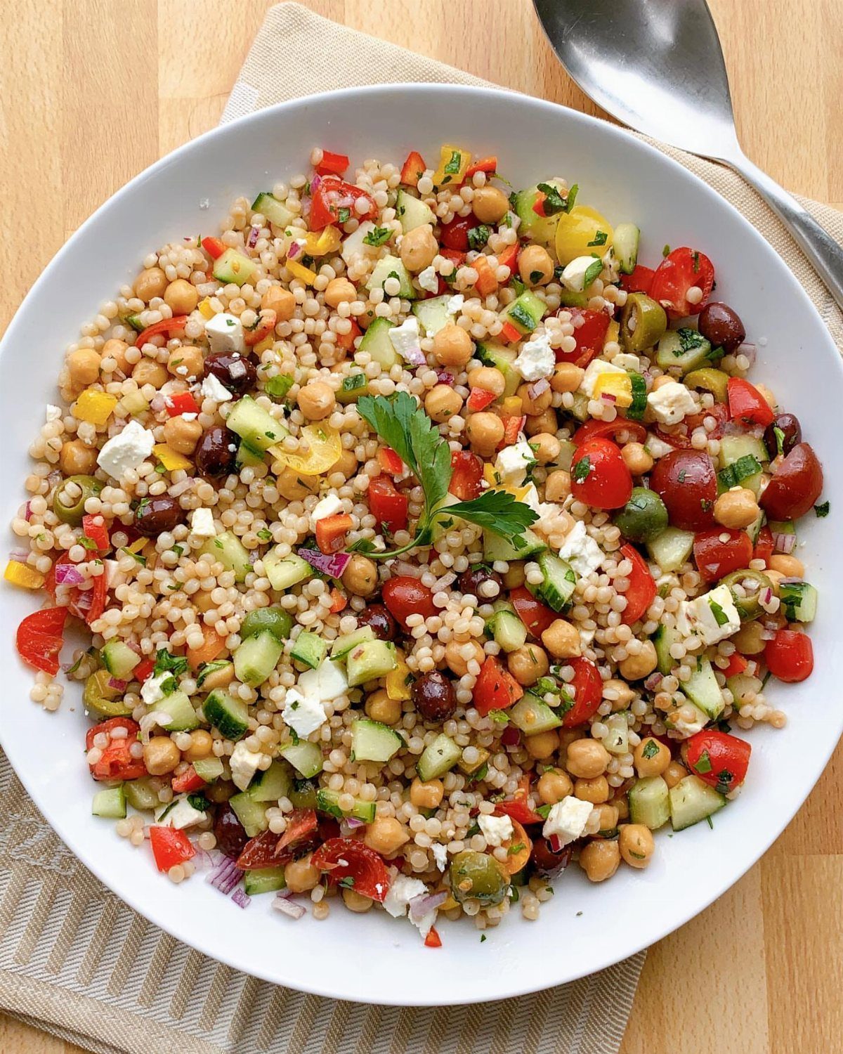 Pearl couscous salad with cherry tomatoes, cucumbers, chickpeas, and crumbled feta cheese.