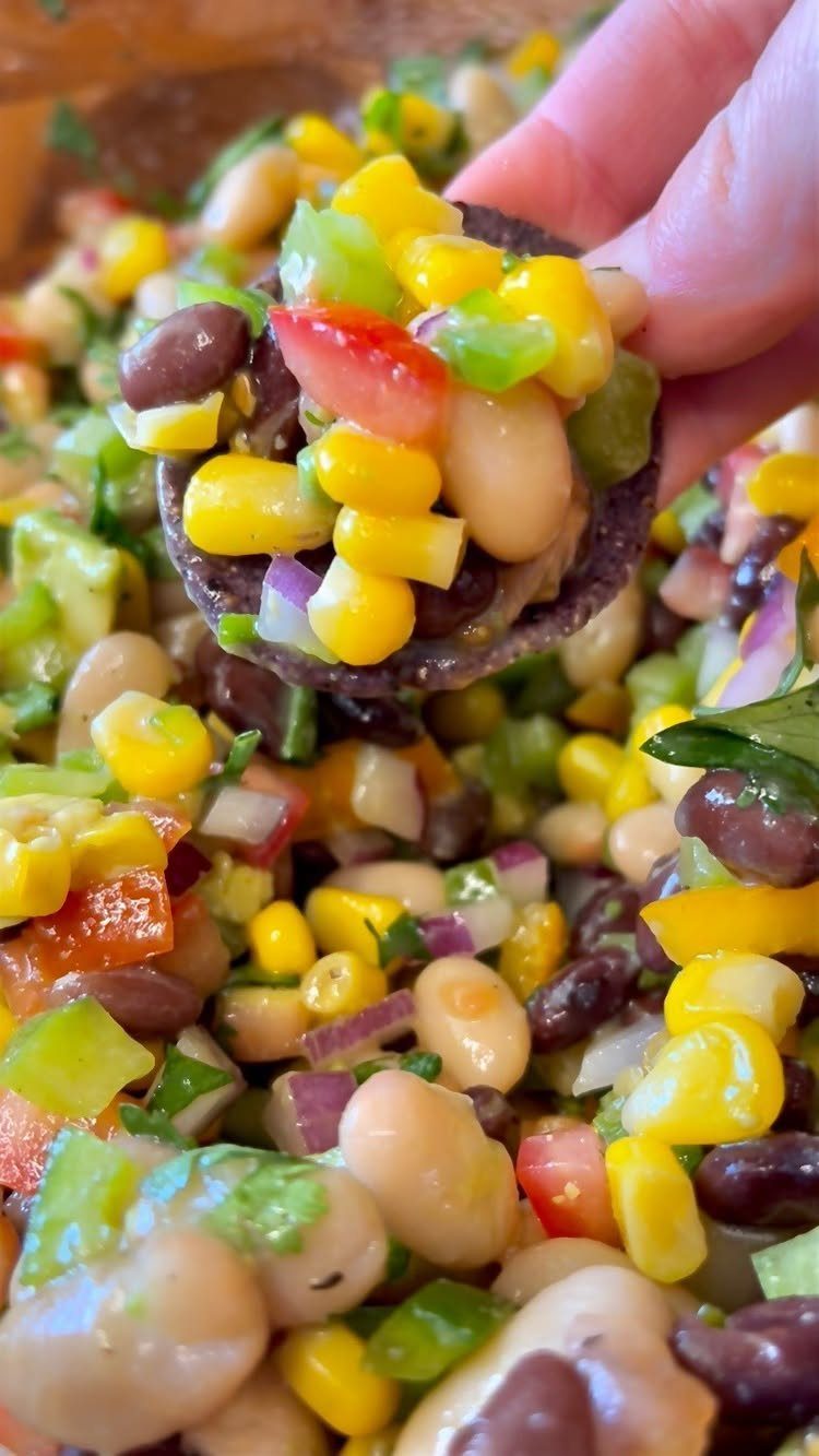 Cowboy caviar bean salad with corn and peppers scooped onto a tortilla chip