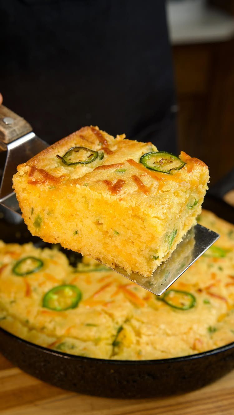 Slice of jalapeño cornbread with melted cheese lifted from a cast-iron skillet.