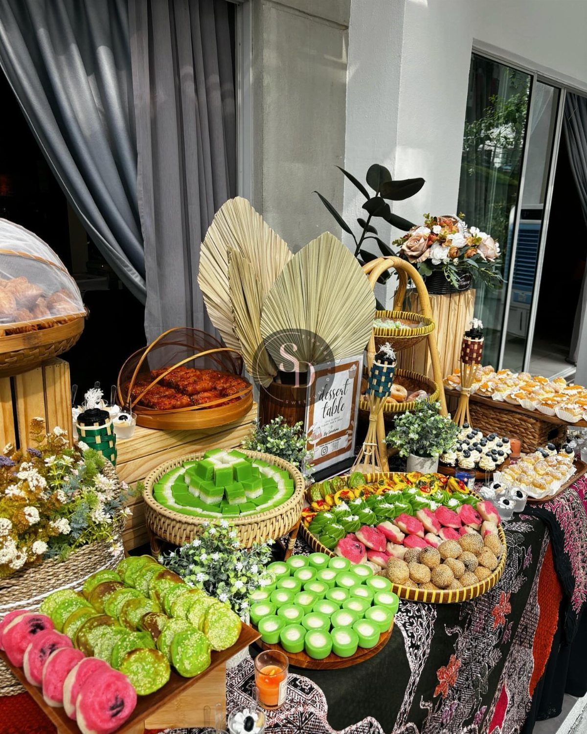 Colorful Asian desserts in woven baskets on a dark patterned fabric tablecloth.