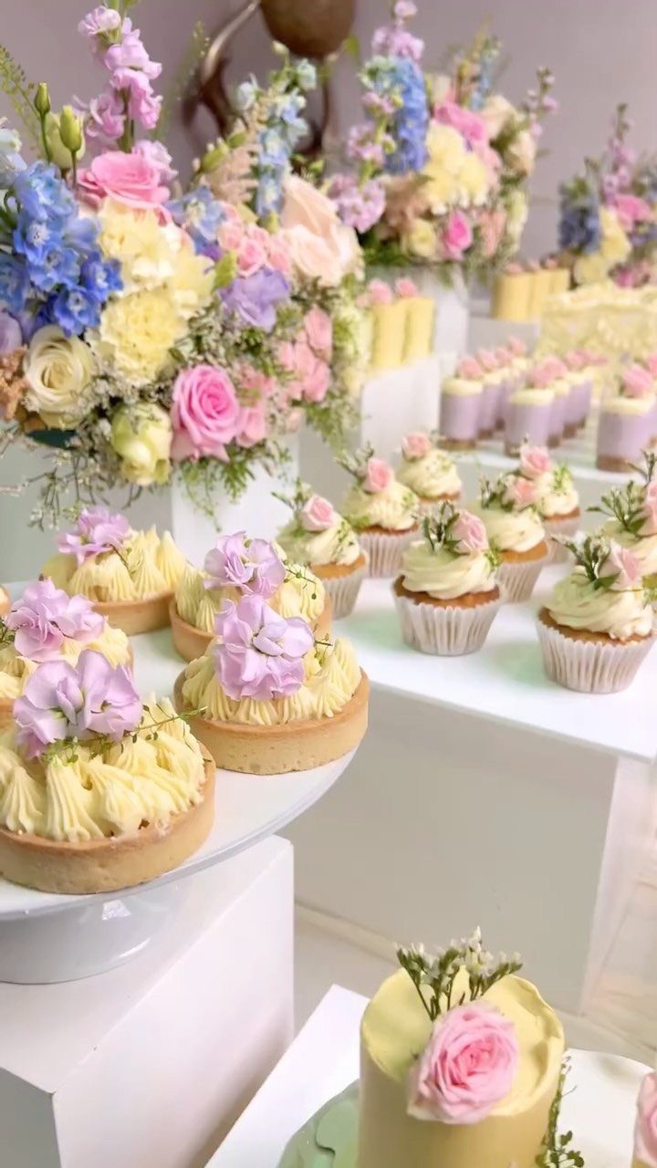 Yellow tarts and cupcakes paired with lush pink, blue, and yellow floral arrangements.