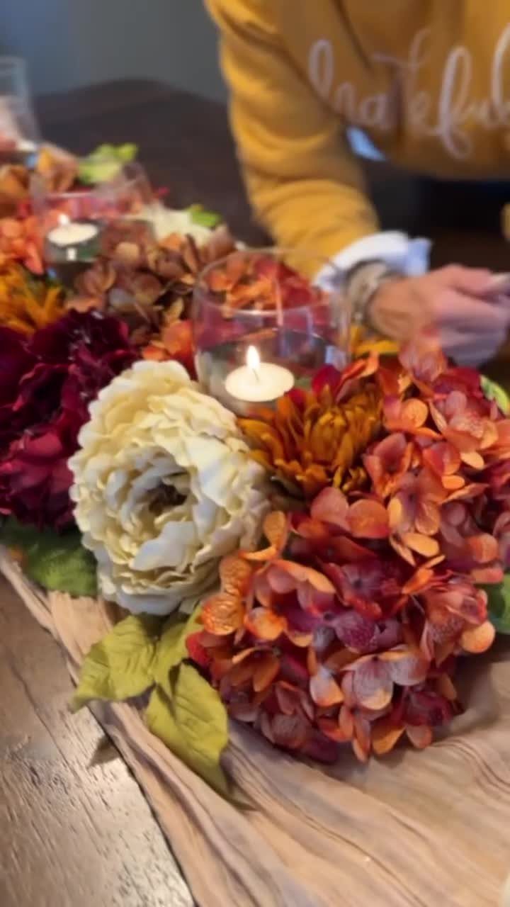 Autumn floral arrangement with tea light candles on a tan table runner.