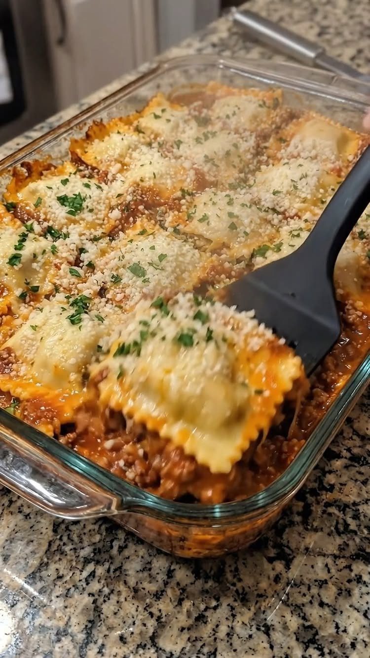 Ravioli casserole with melted cheese and red sauce in a glass baking dish.
