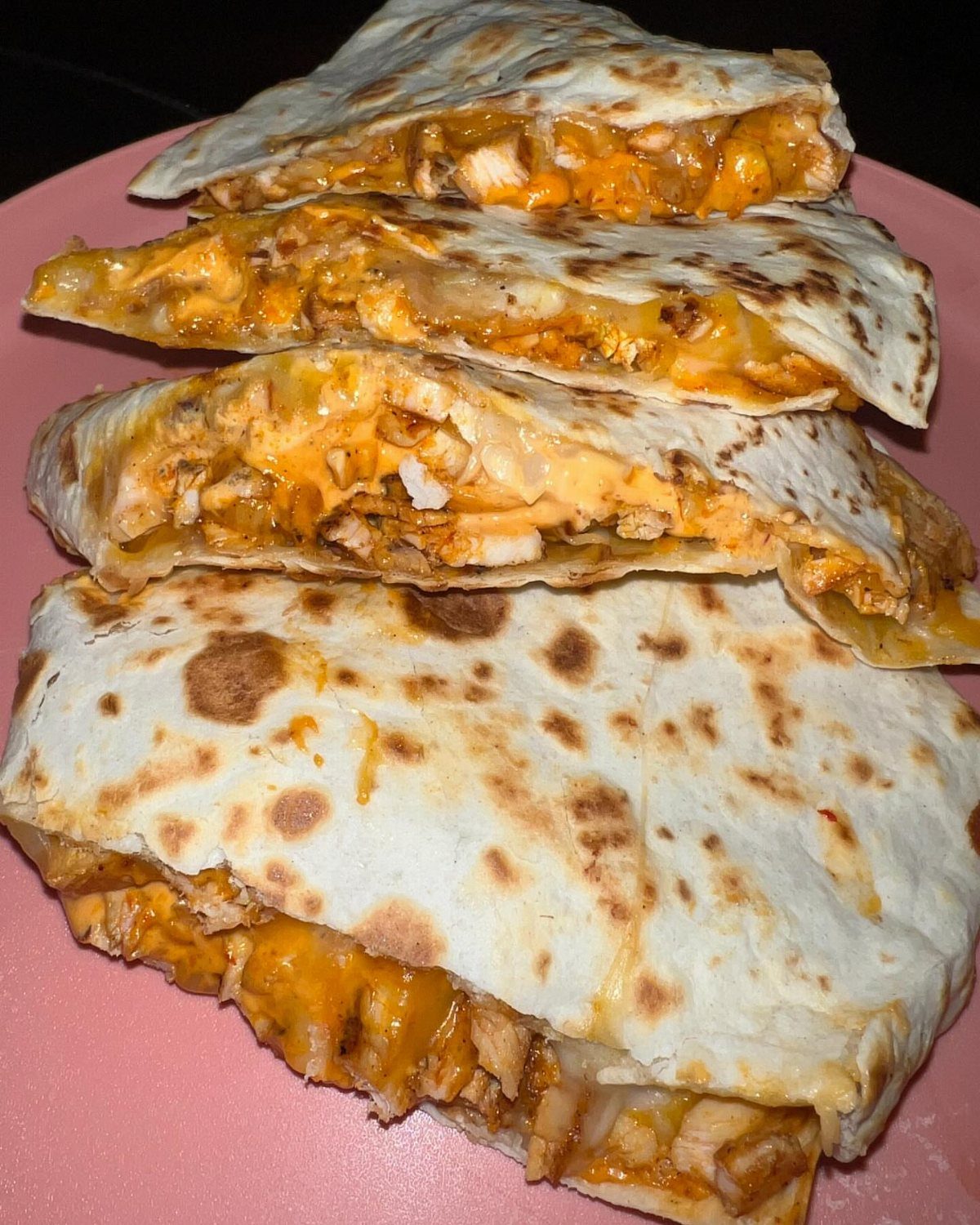 Stacked barbecue chicken quesadillas with melted cheese on a pink plate