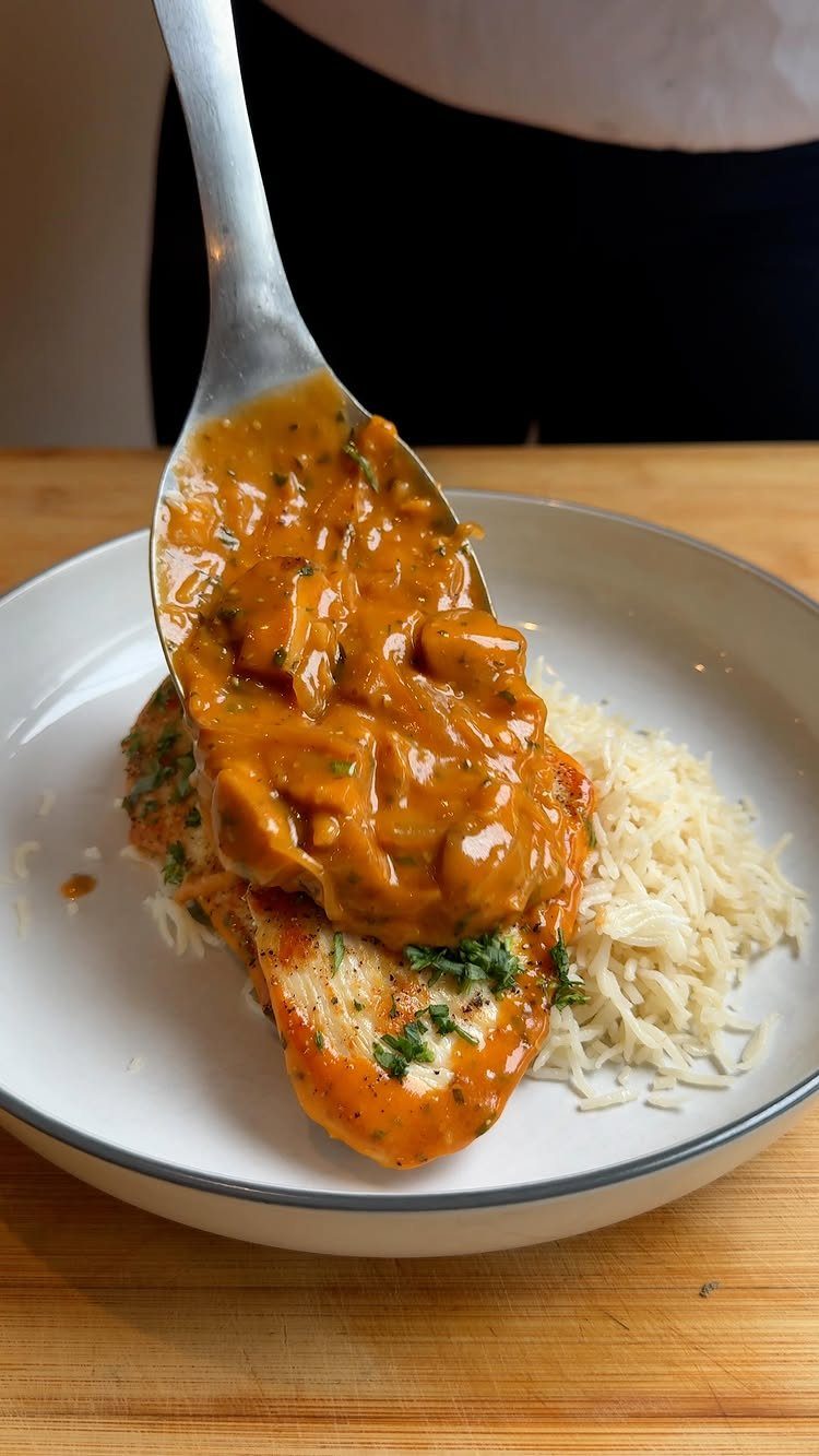 Creamy chicken stroganoff sauce being spooned over toast and white rice.