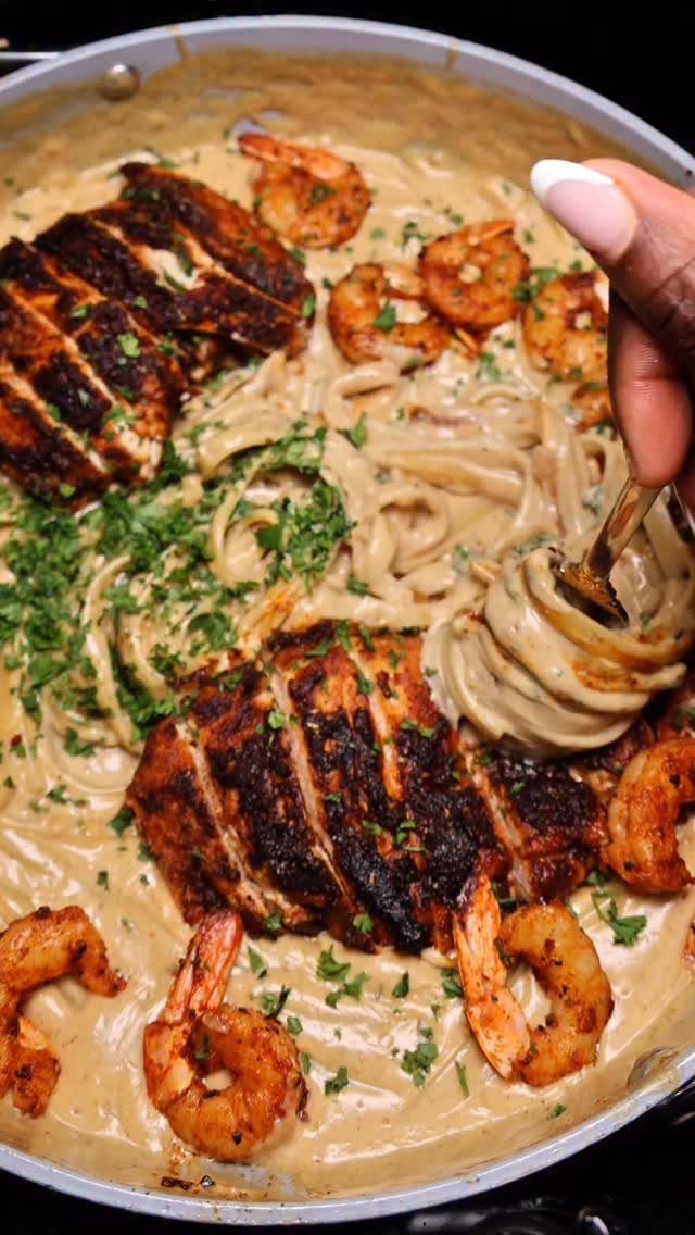Blackened chicken and shrimp with pasta in a creamy sauce in a pan