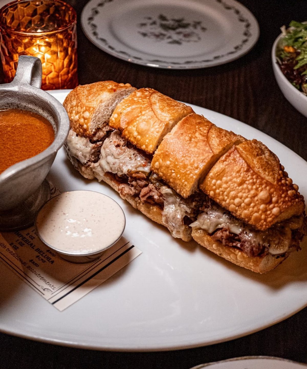 French dip sandwich with sliced beef and melted cheese served with dipping broth.